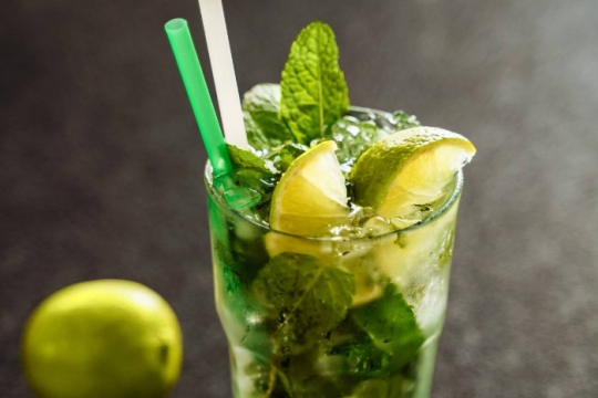 Mojito in a highball glass with limes in the background